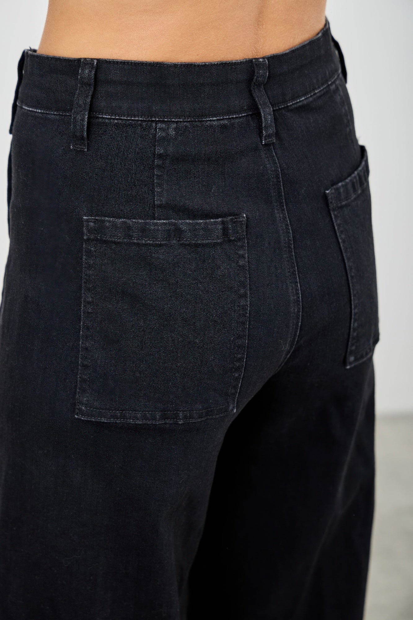 Black jeans with a plain background detailed back view