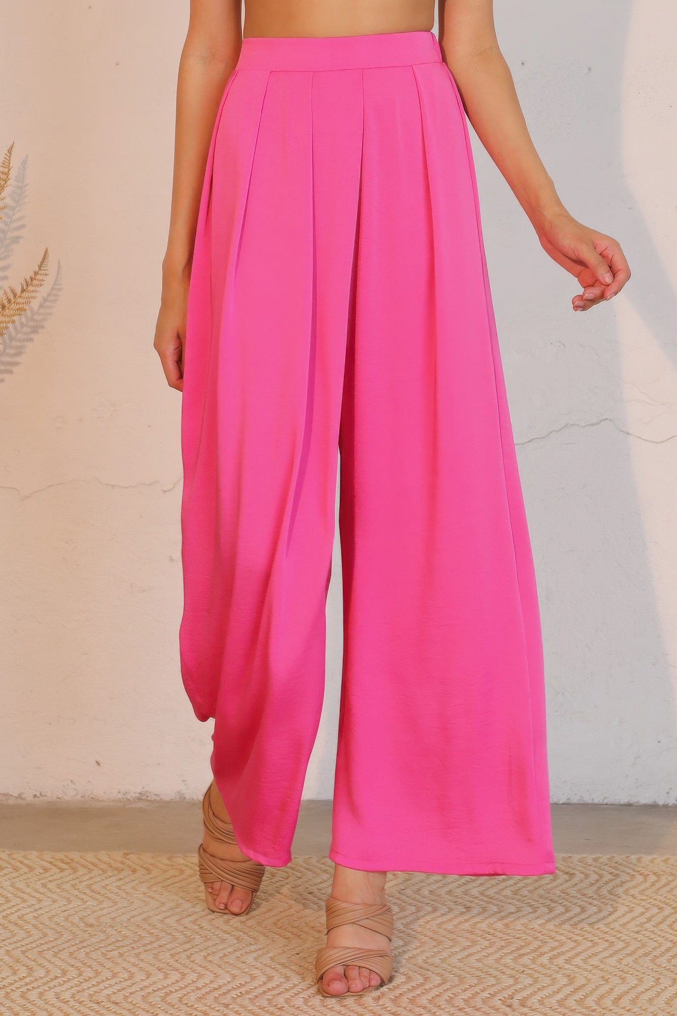 Person wearing bright pink wide-leg pants against a neutral background