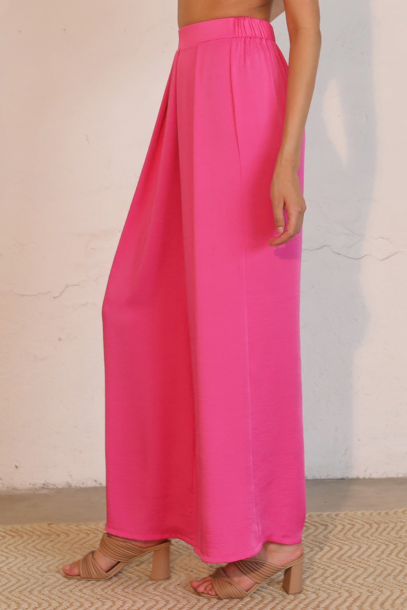 Person wearing bright pink wide-leg pants against a neutral background side view
