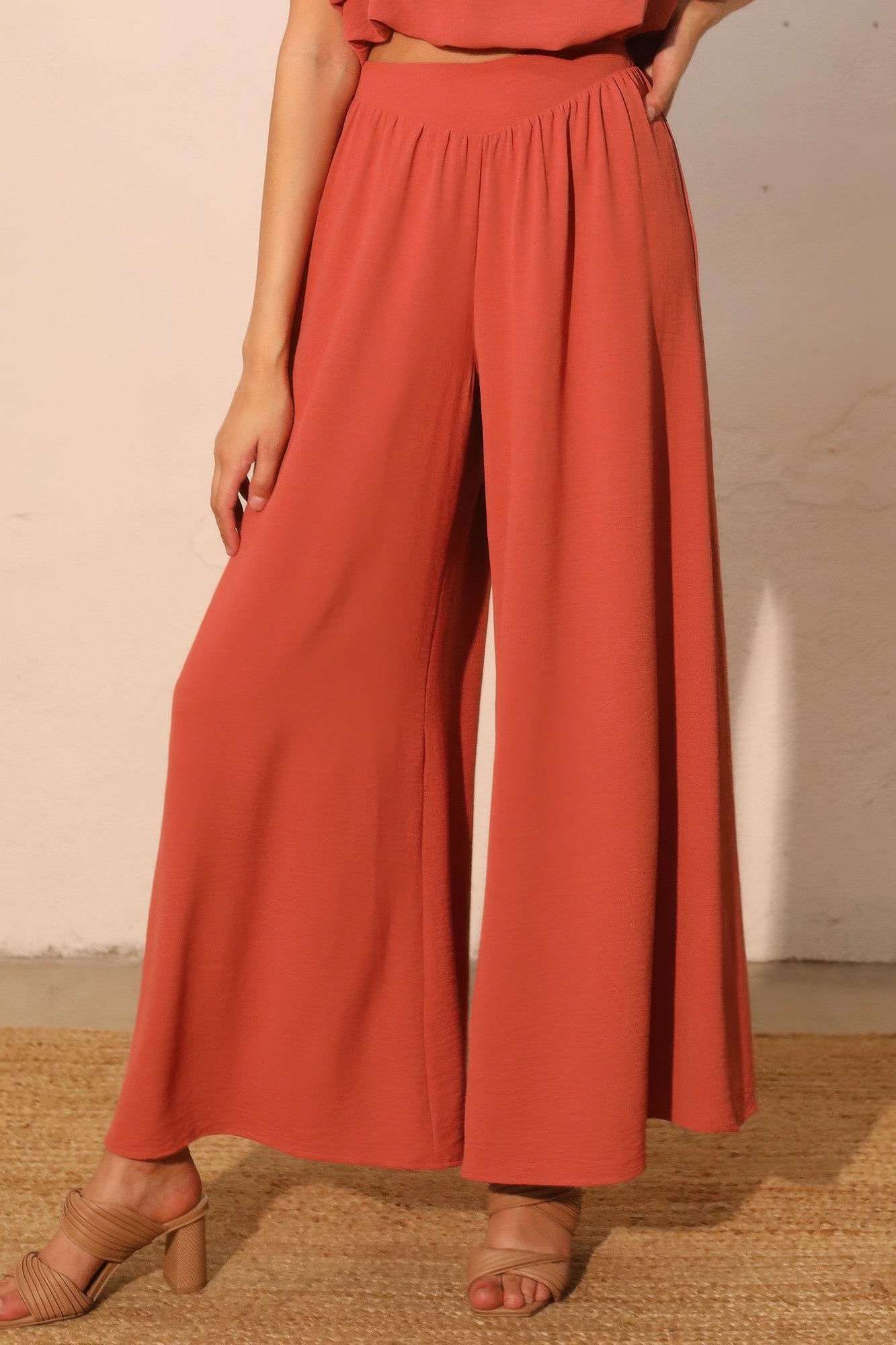 Person wearing coral-colored wide-leg pants against a neutral background