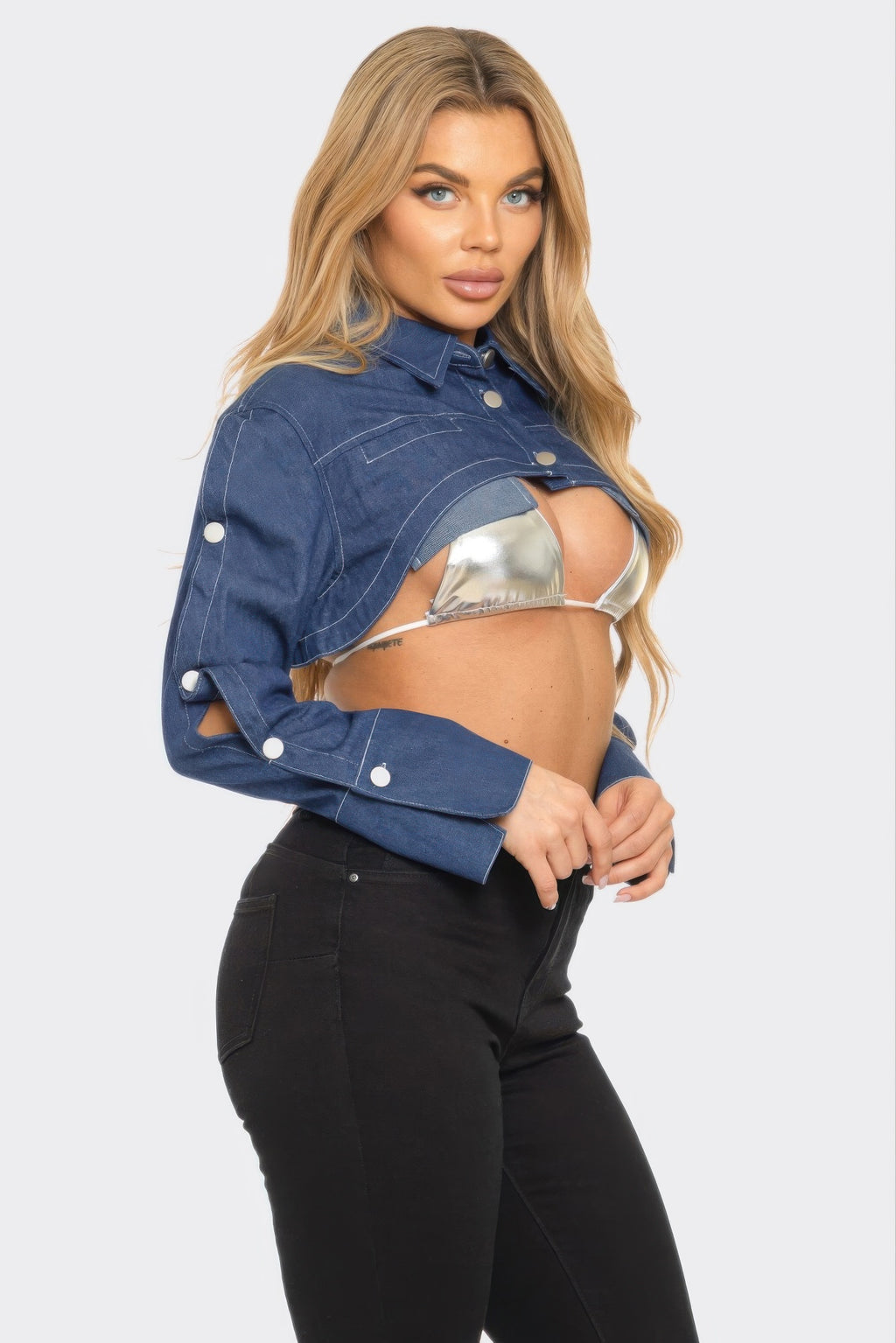 Woman wearing a denim jacket over a metallic top on a white background