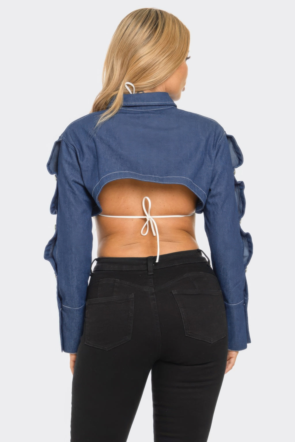 Person wearing a blue denim jacket with a cutout design on a white background