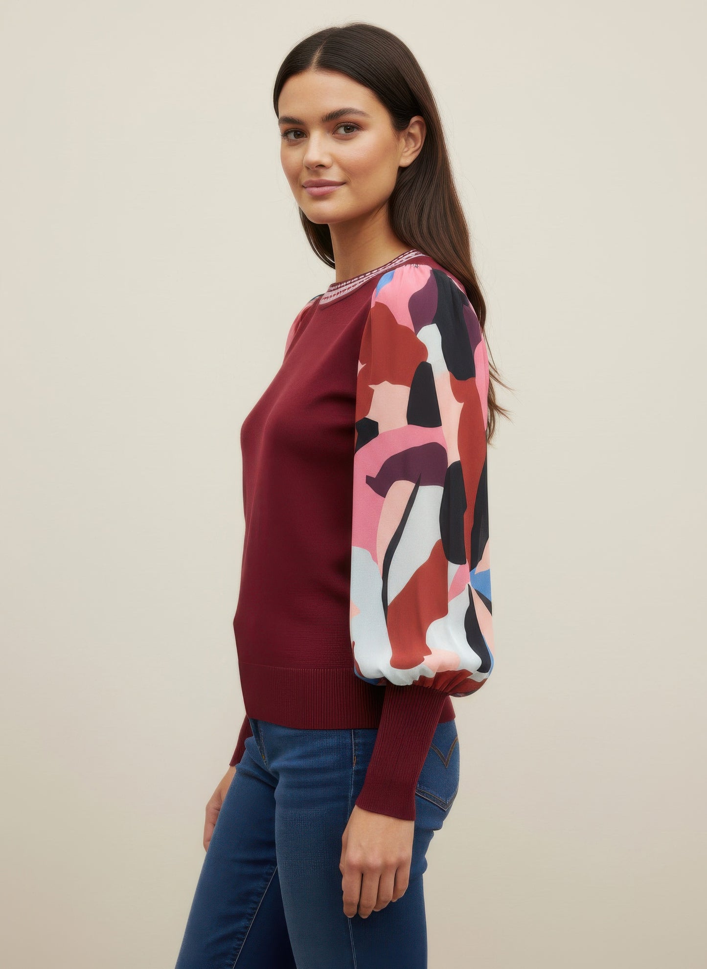 Woman wearing a burgundy rio & rian sweater with abstract pattern sleeves side view