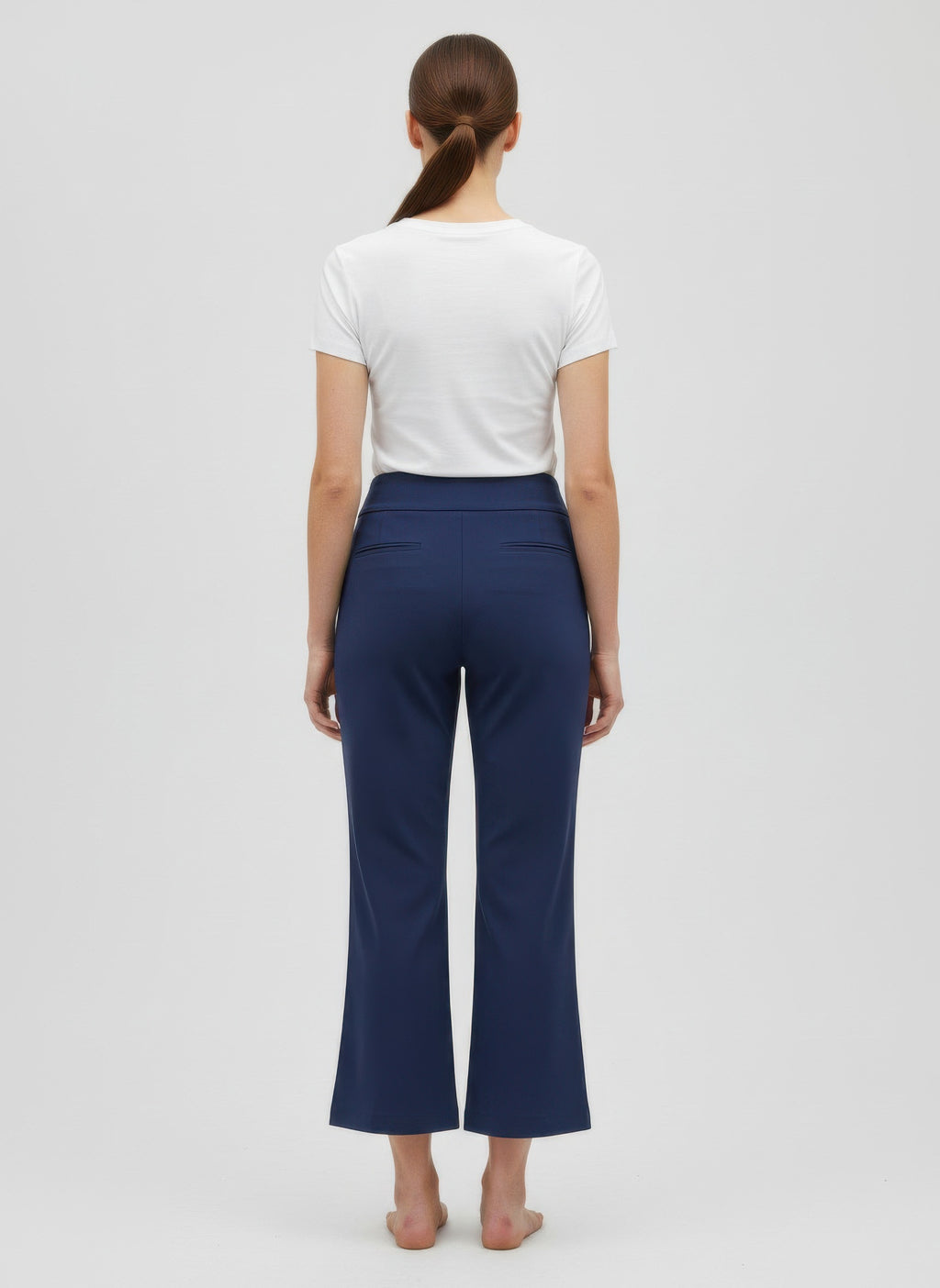 Person wearing navy pants and a white shirt on a light gray background back view