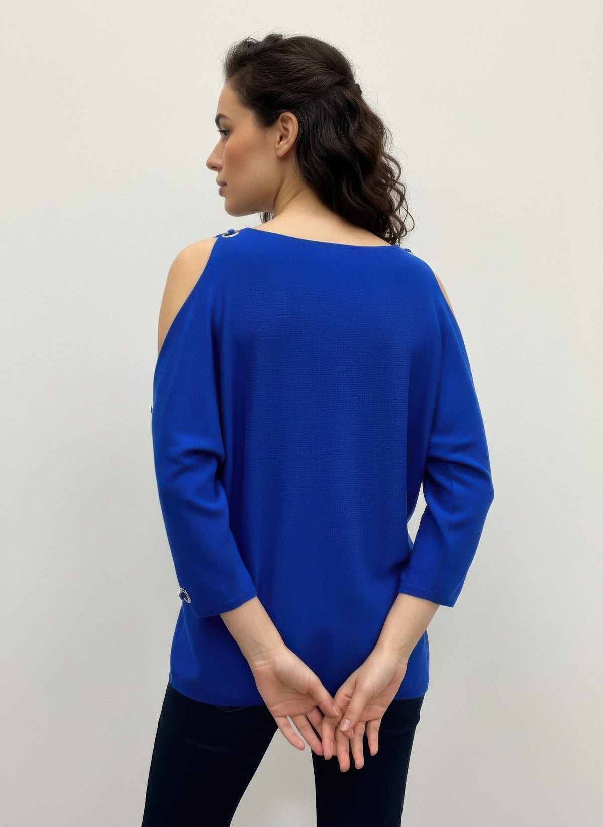 Woman wearing a blue Cable & Gauge Pullover Sweater with cut-out shoulders. Back view