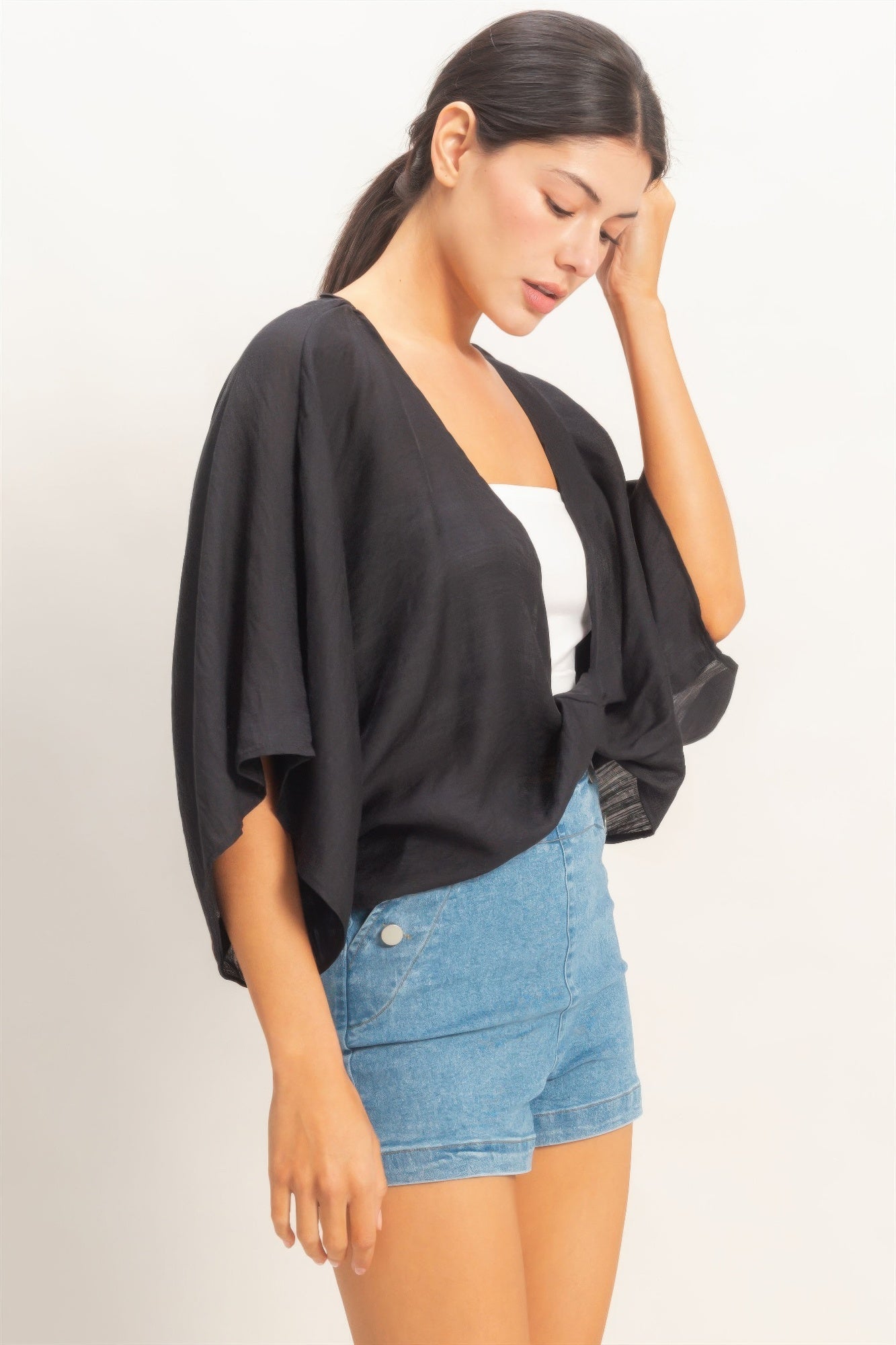 Woman wearing a black oversized twist knot cardigan angle view