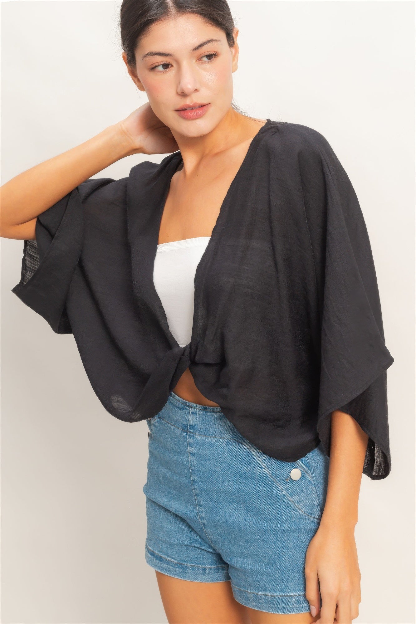 Woman wearing a black oversized twist knot cardigan top front view
