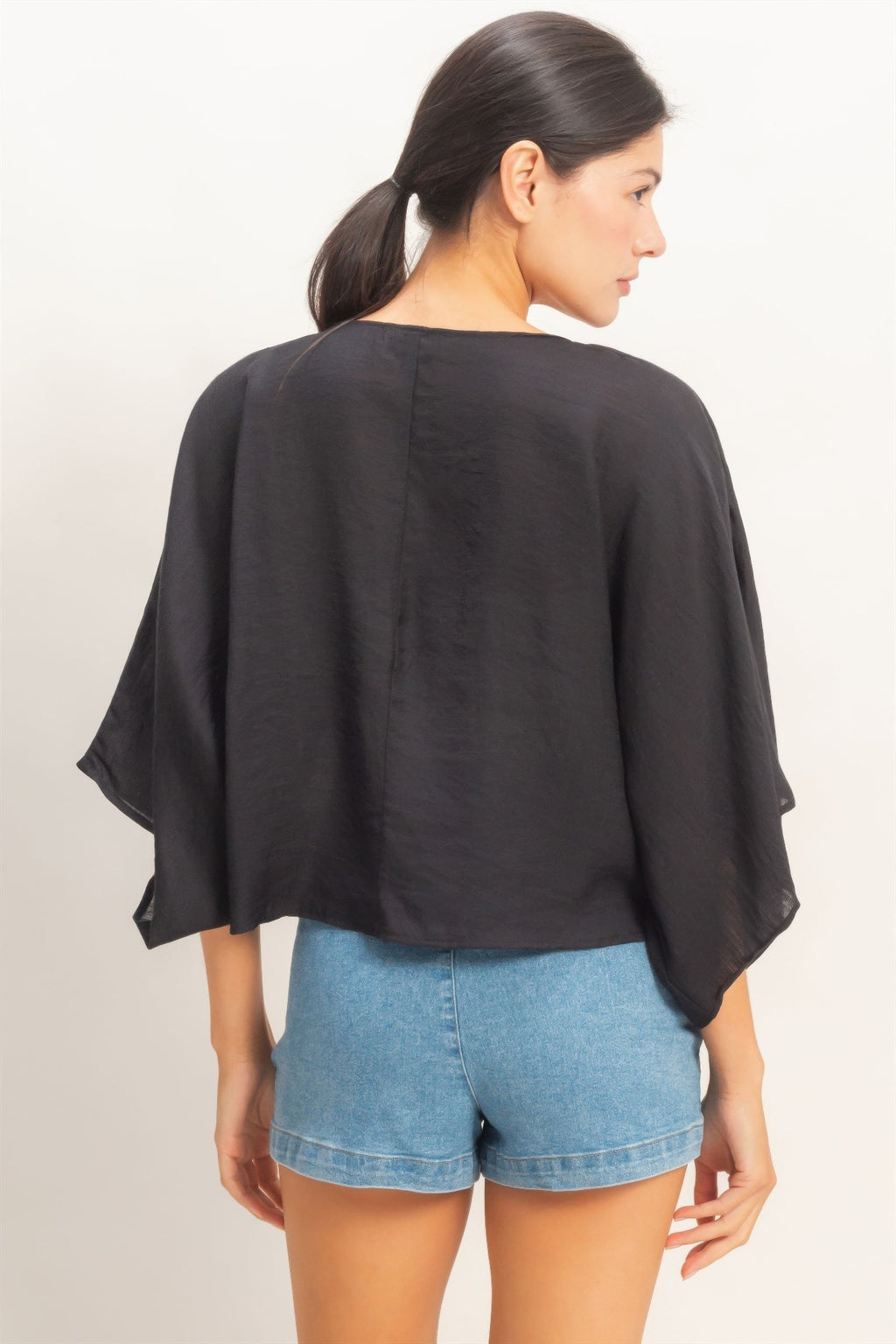 Woman wearing a black oversized twist knot cardigan top back view