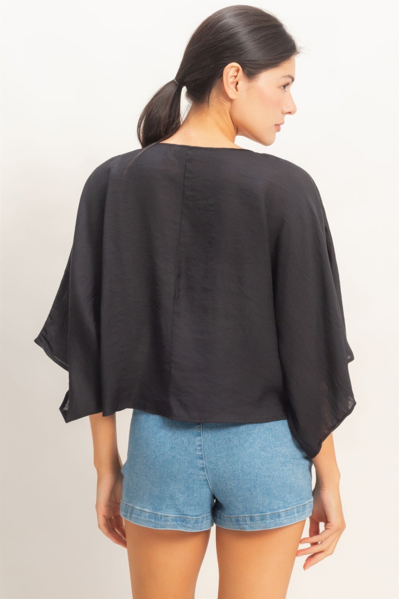 Woman wearing a black oversized twist knot cardigan top back view