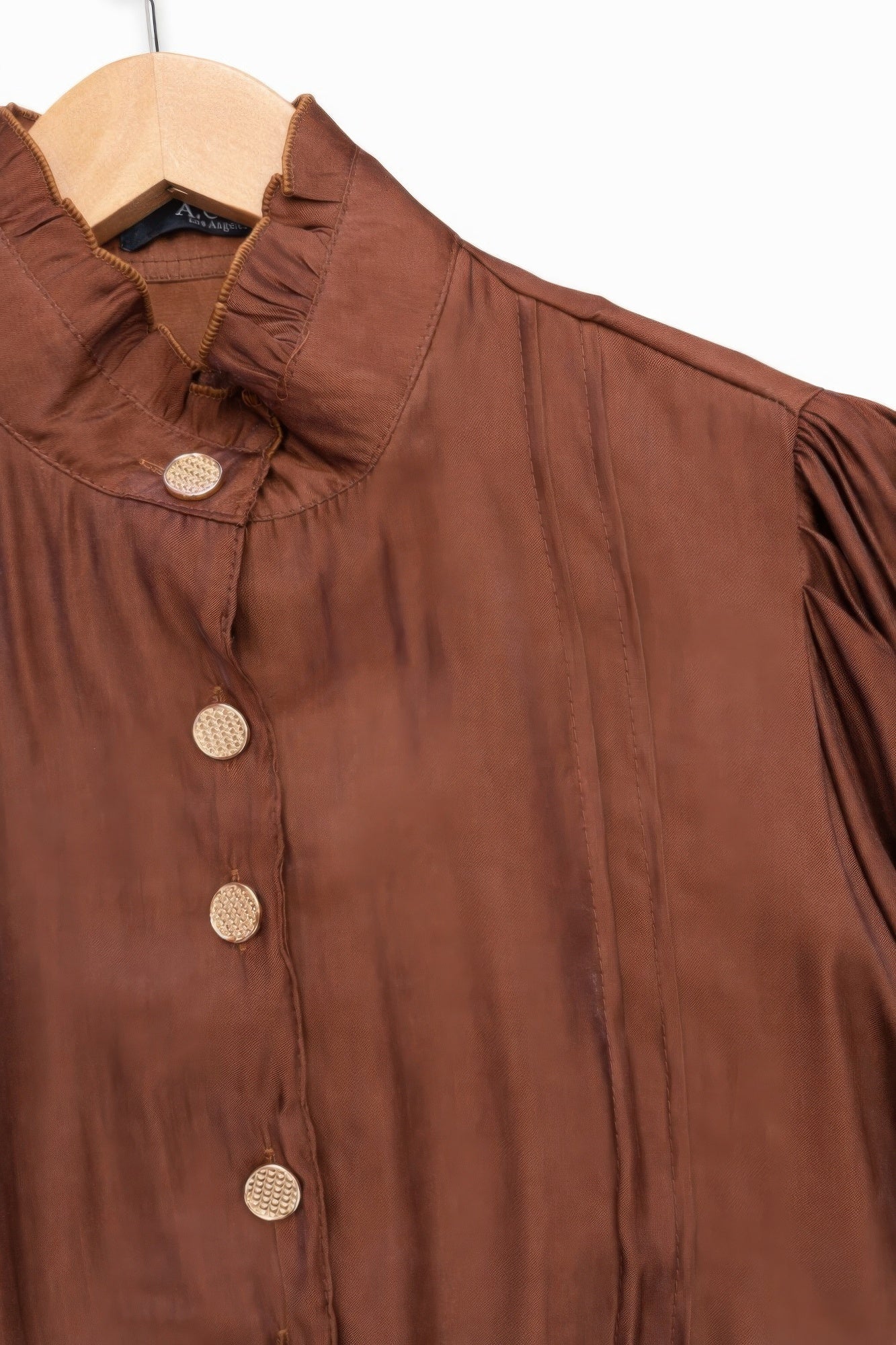 Brown Victorian blouse with ruffled collar and buttons on a hanger close up