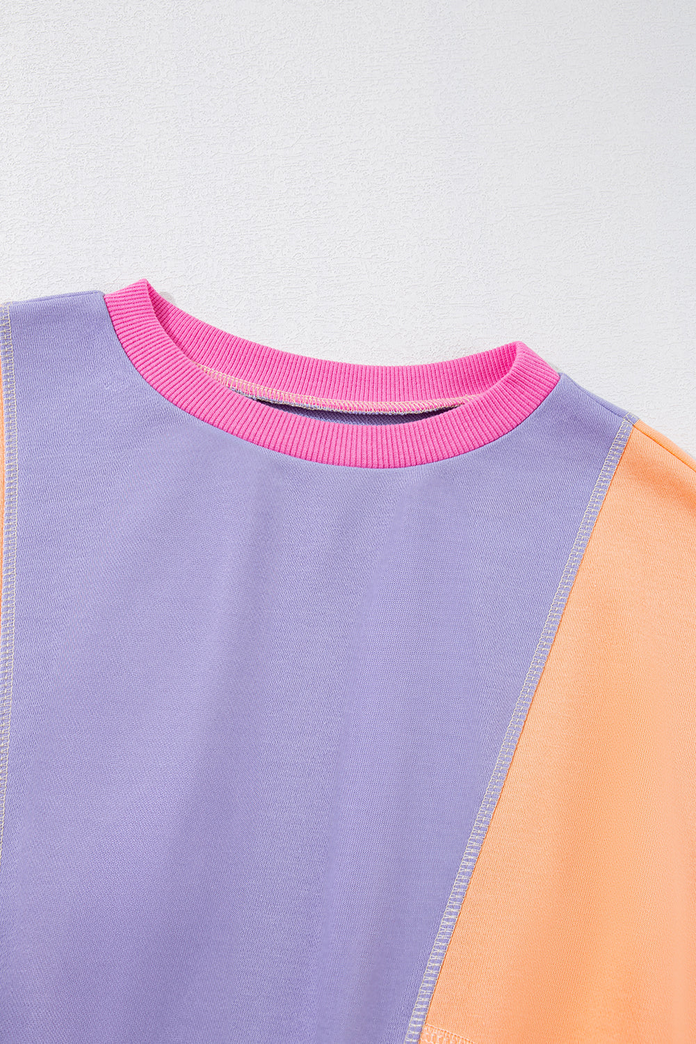 Close-up of the collar of a vibrant colorblock sweatshirt, focusing on the playful mix of colors and stitching details.