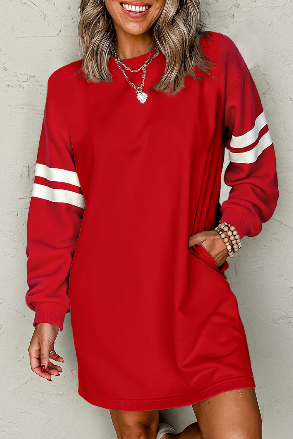 Close-up of a model in an red athletic dress, featuring side pockets and sporty white stripes