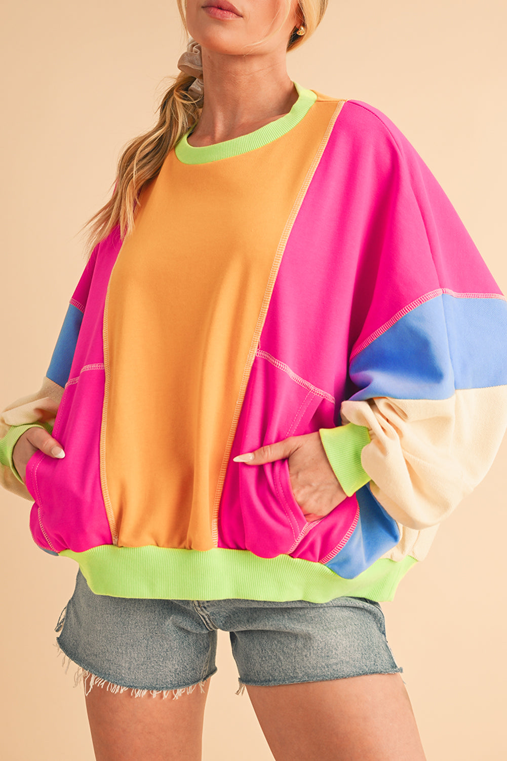 Close-up of a model in a vibrant colorblock sweatshirt with pockets, emphasizing the stylish layering and bright colors.