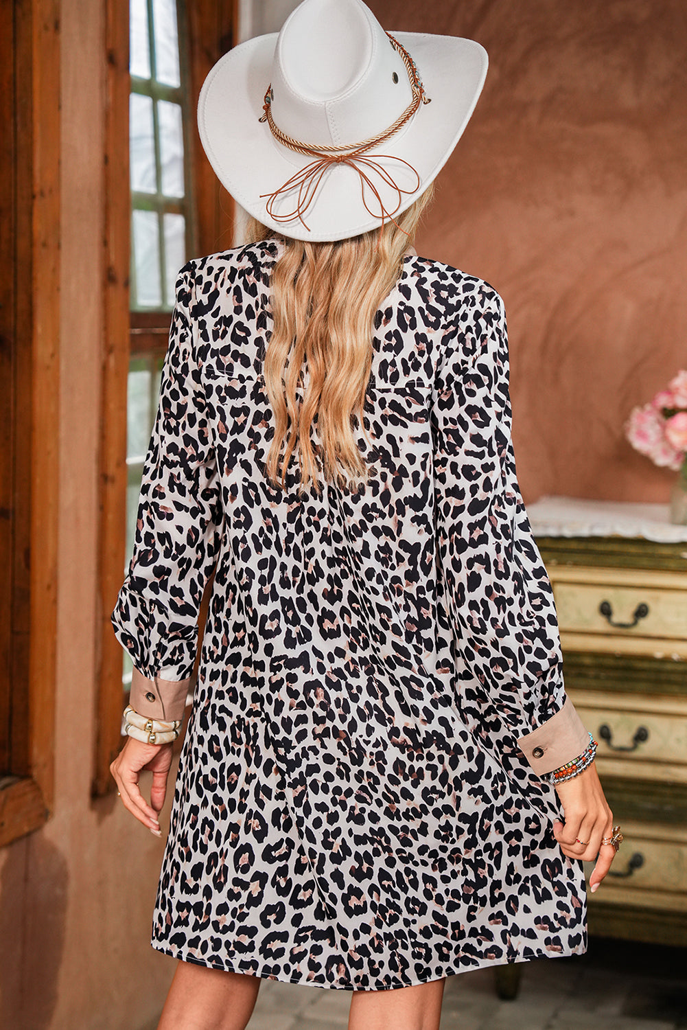 Back view of a model in a leopard print dress, showcasing long sleeves and a stylish collar,