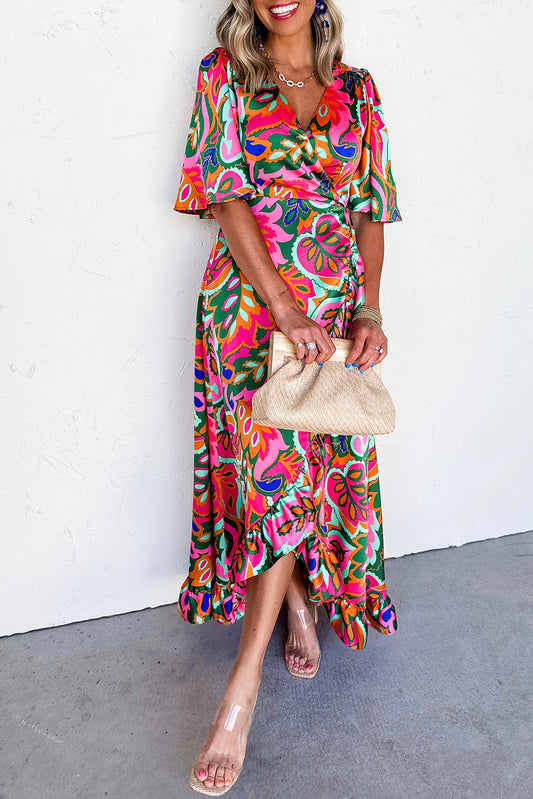 Woman wearing a colorful patterned dress holding a beige clutch against a white background