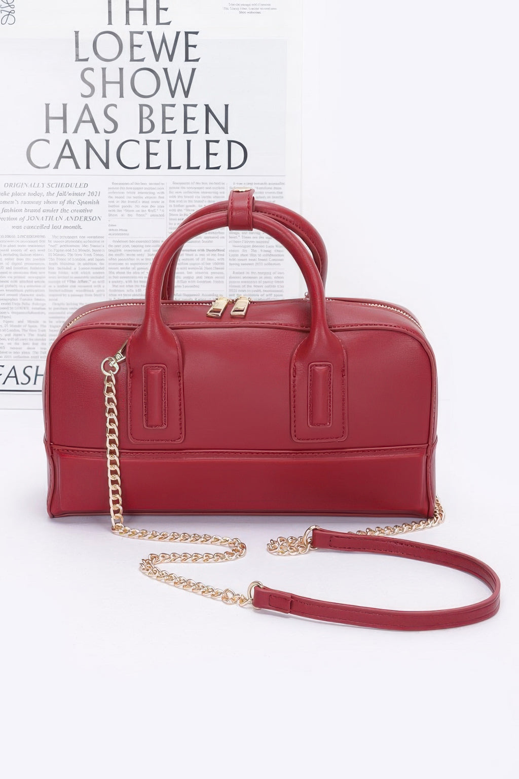 Red handbag with gold chain strap on a white background, featuring text about a show being cancelled.