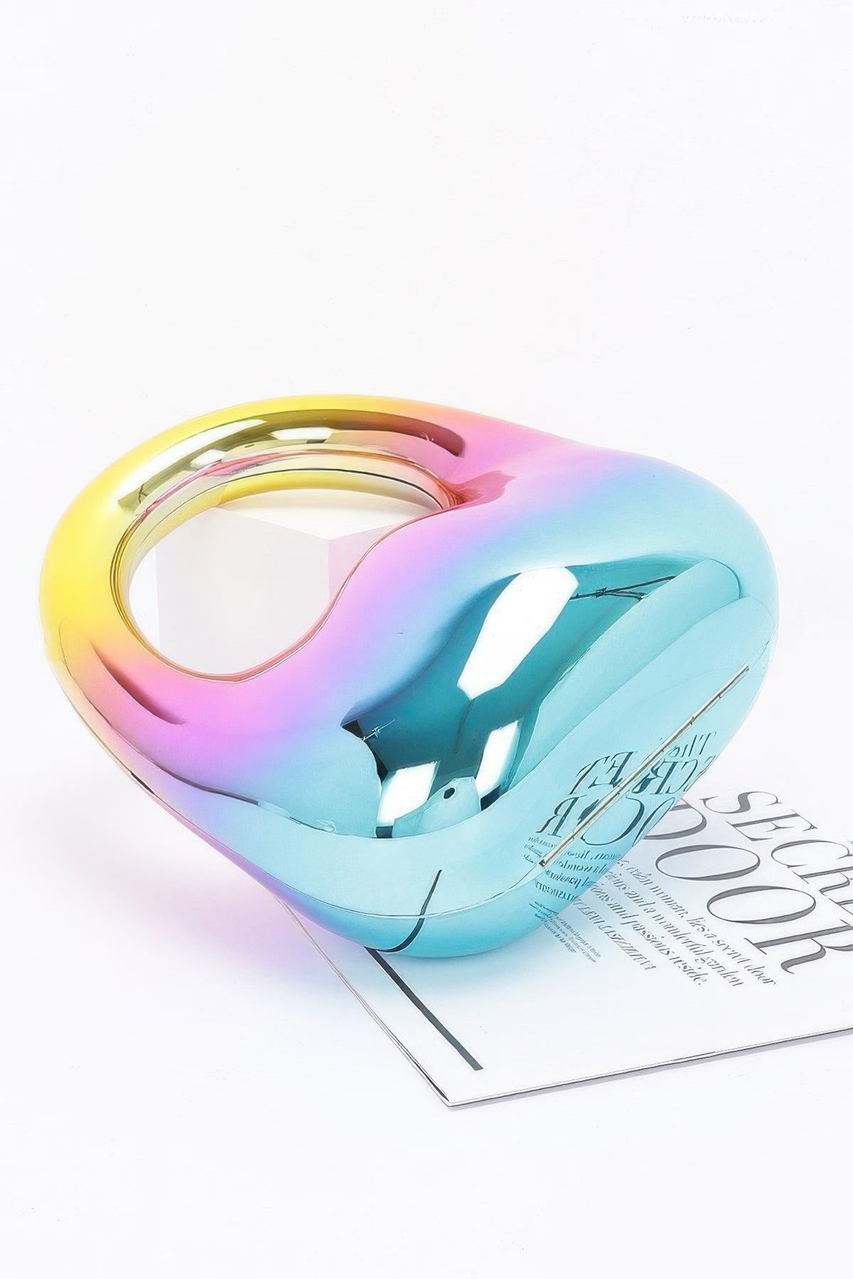 Multicolored heart-shaped object on a white surface with a magazine underneath