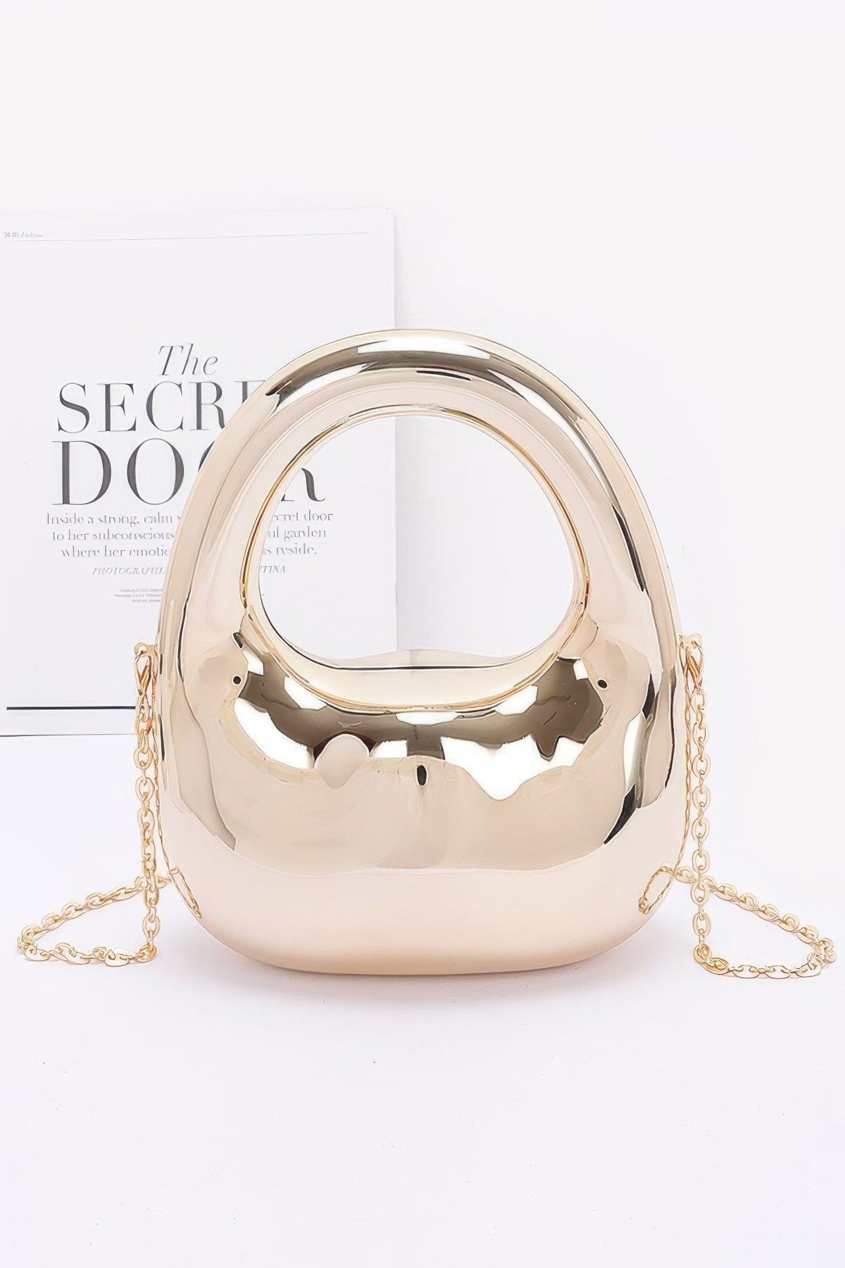 Gold metallic handbag with chain strap on a white background