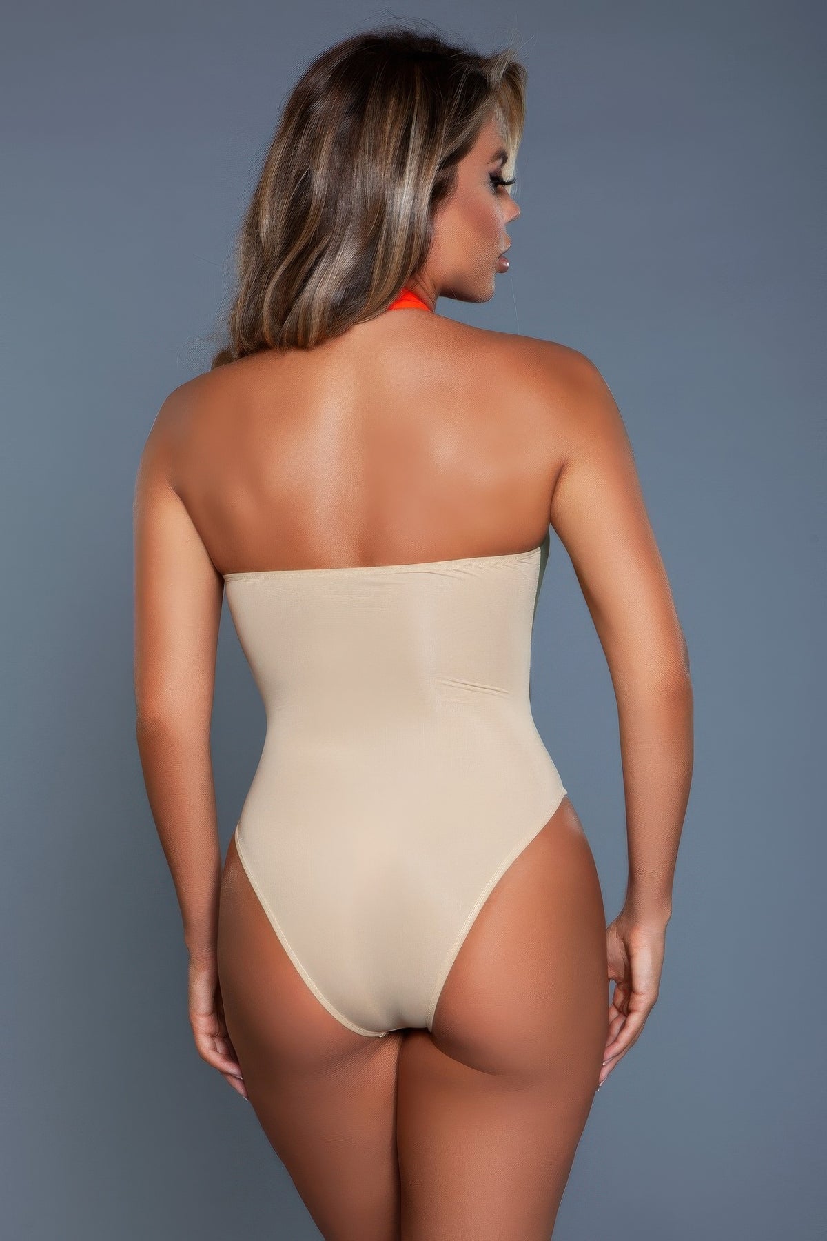 Woman wearing a beige strapless bodysuit against a gray background