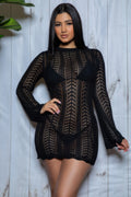 Woman wearing a black crochet dress against a light wooden panel background
