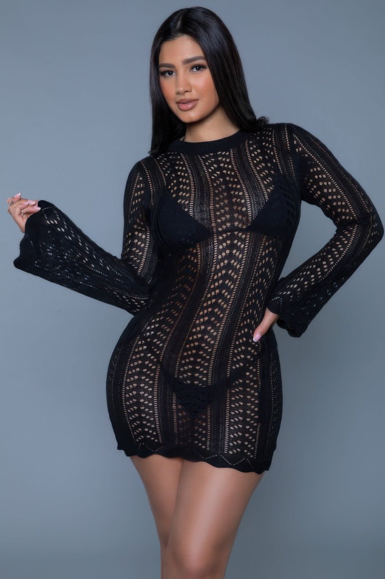 Woman wearing a black patterned dress against a gray background front vew