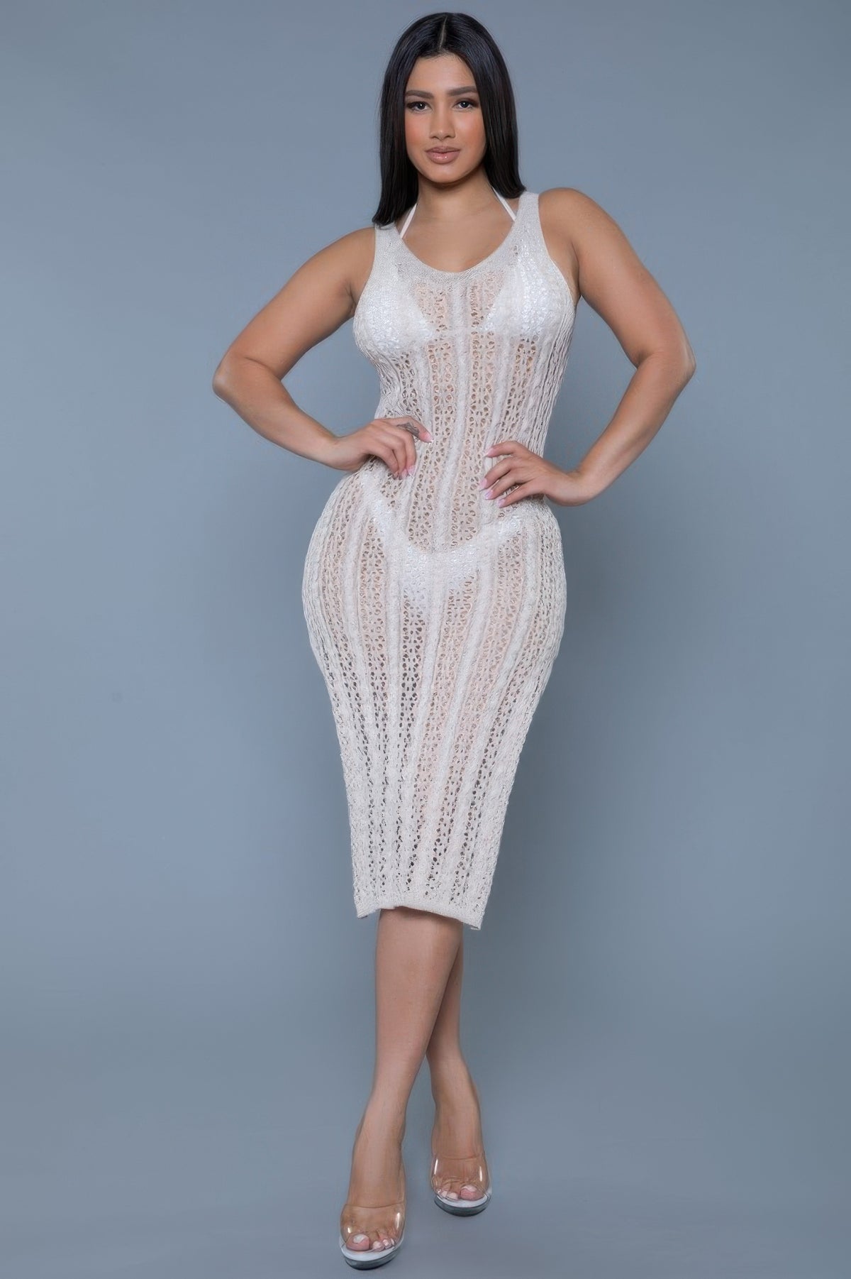 Woman wearing a white lace dress against a gray background front view