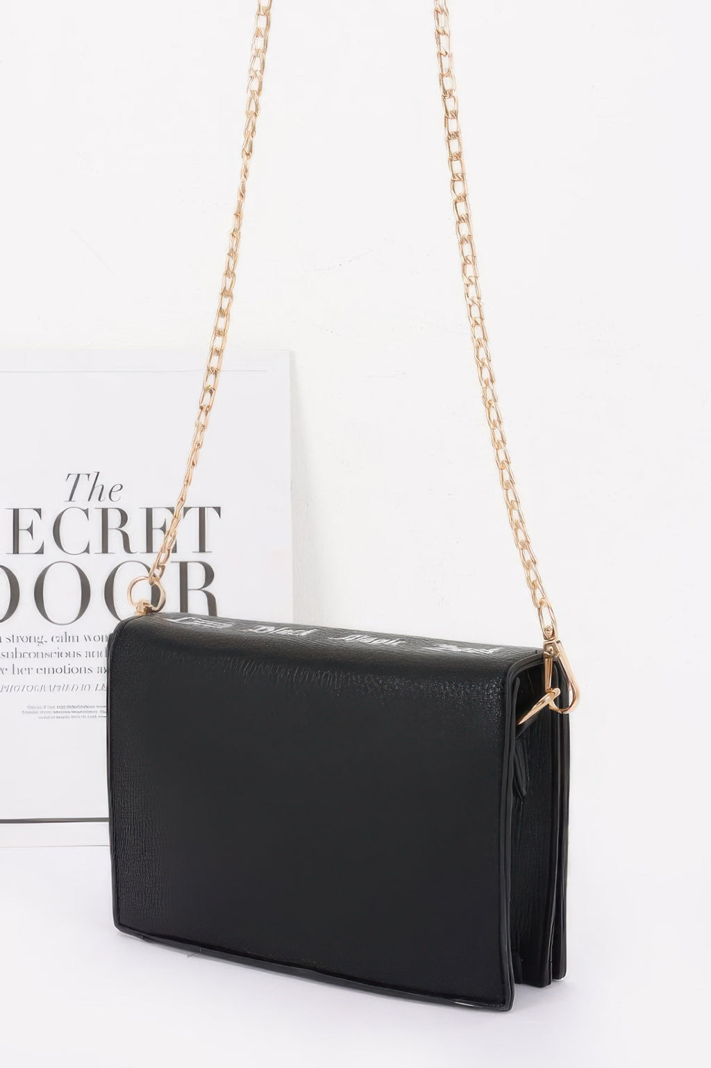 Clutch bag with "Little Black Magic Book” text, back view