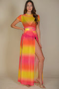 Woman wearing a colorful maxi dress with a gradient of red, orange, and yellow on a beige background