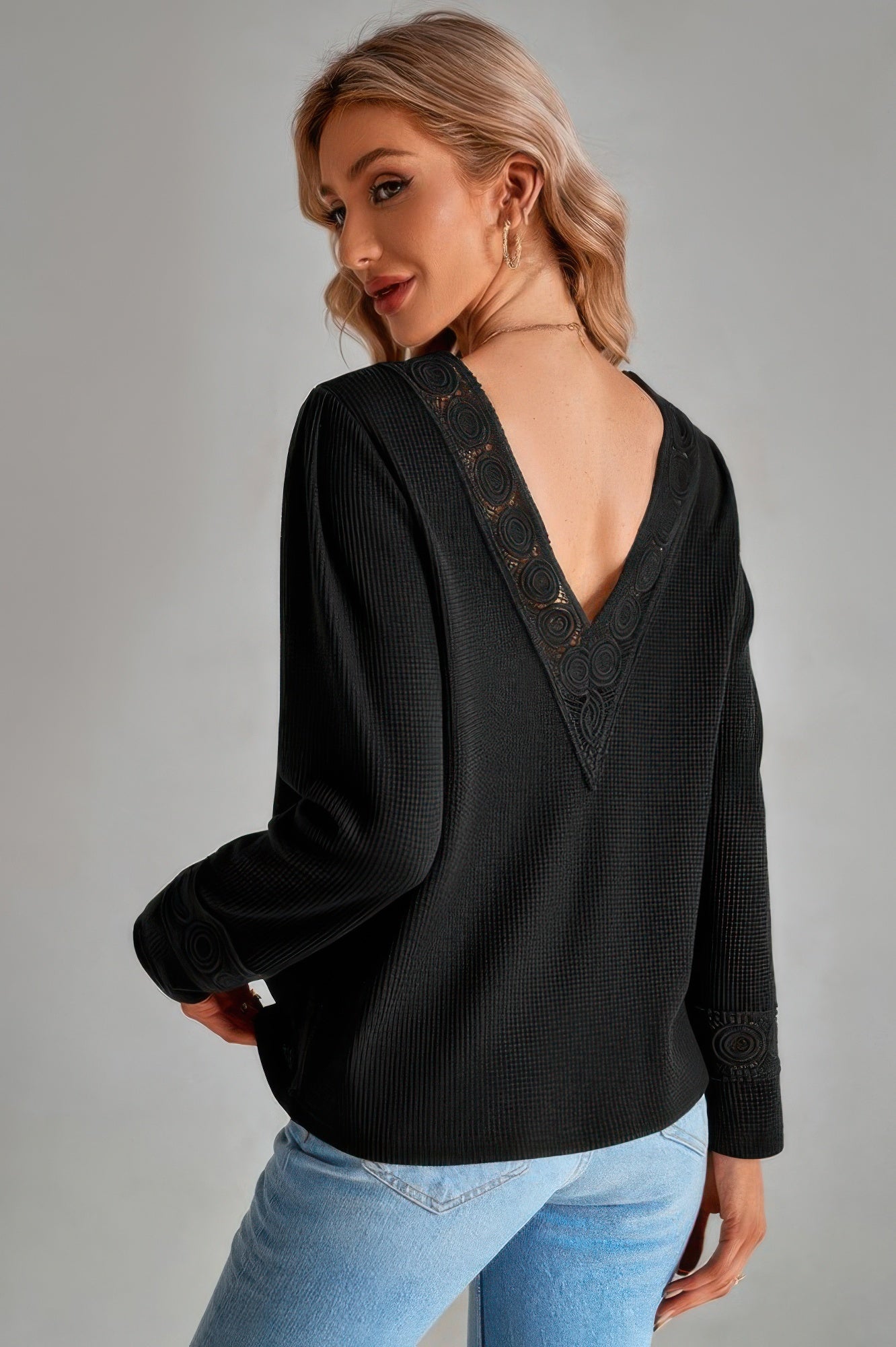 Woman wearing a black blouse with lace detailing back view