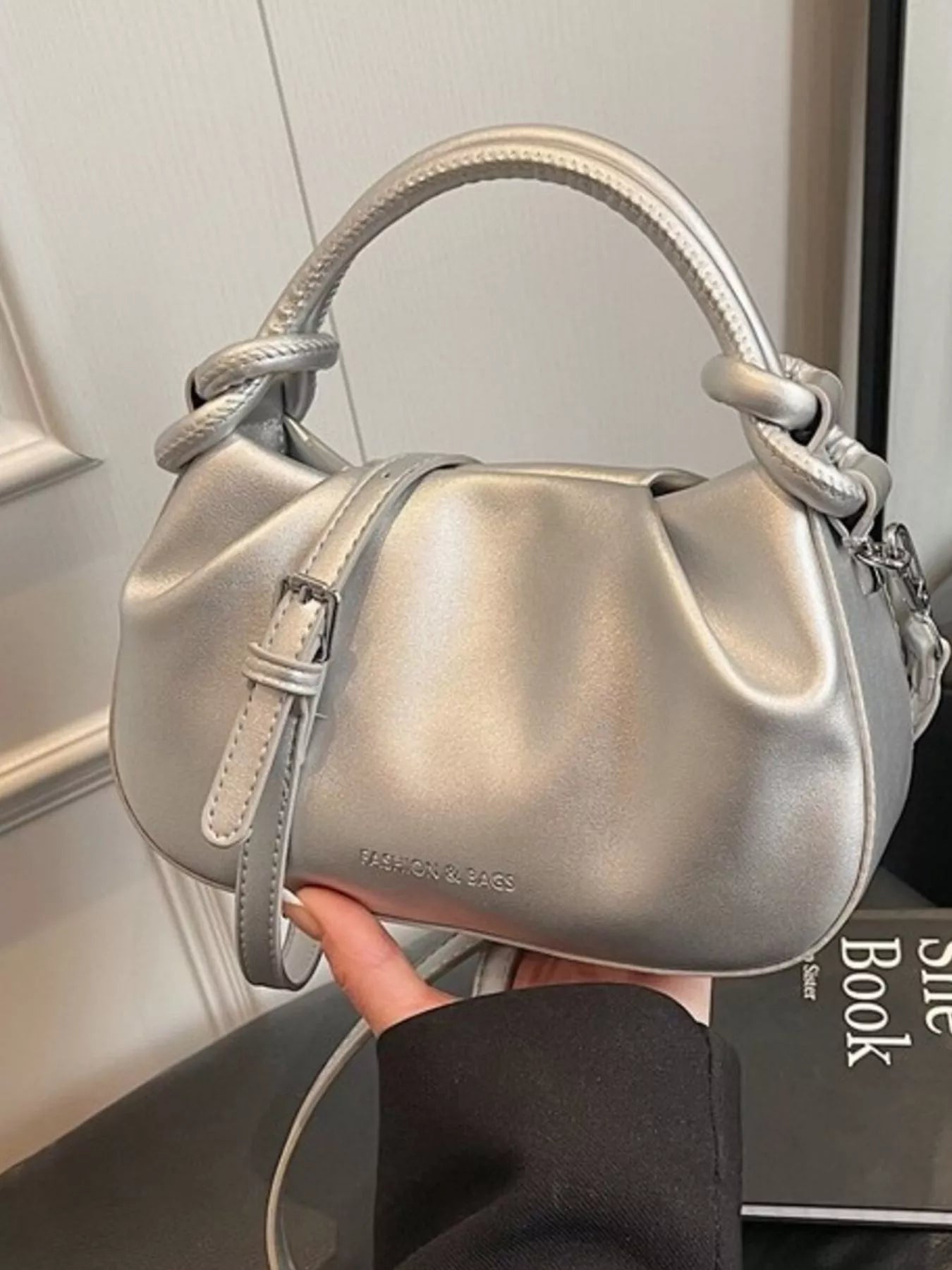 Silver handbag held by a person with a blurred background