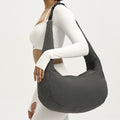 Person wearing a gray shoulder bag on a plain background