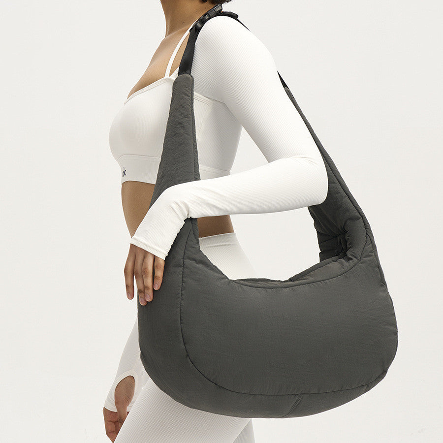 Person wearing a gray shoulder bag on a plain background