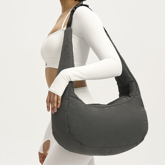 Person wearing a gray shoulder bag on a plain background