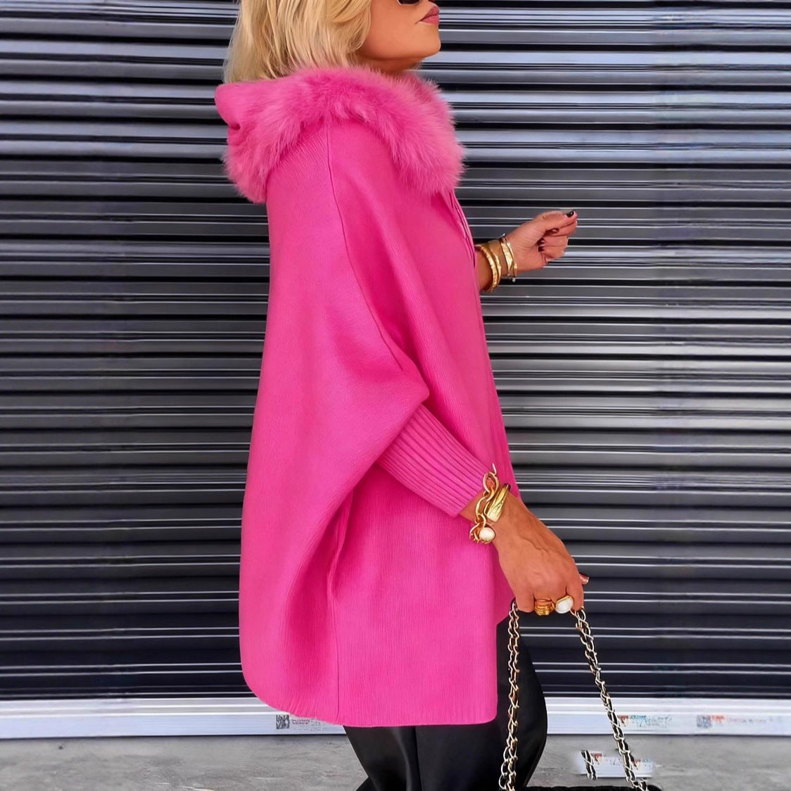 Person wearing a bright pink coat with a fur hood, standing in front of a metallic shutter.