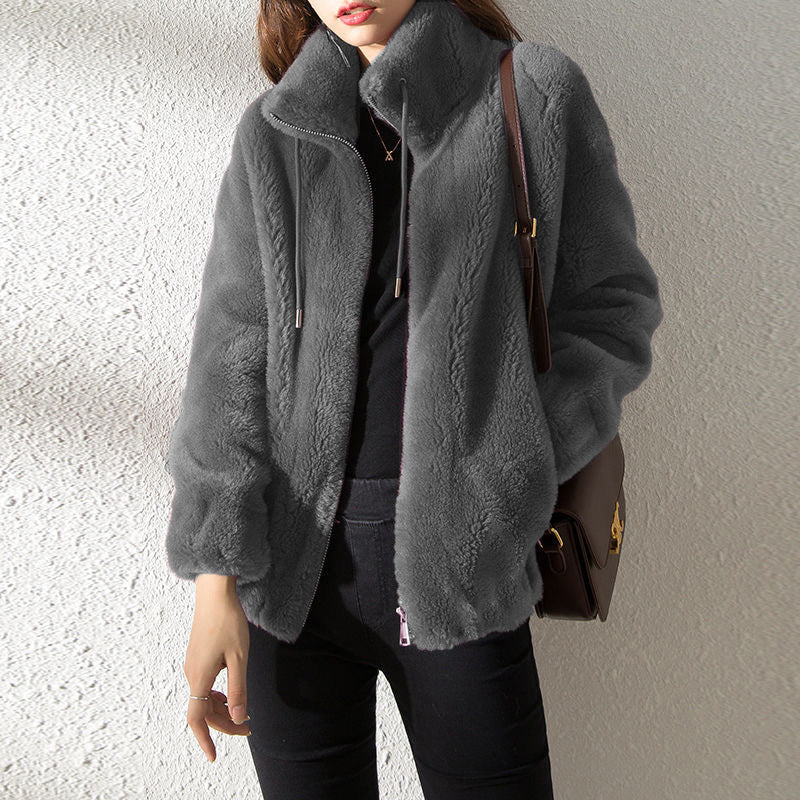 Person wearing a gray fleece jacket with a plain background