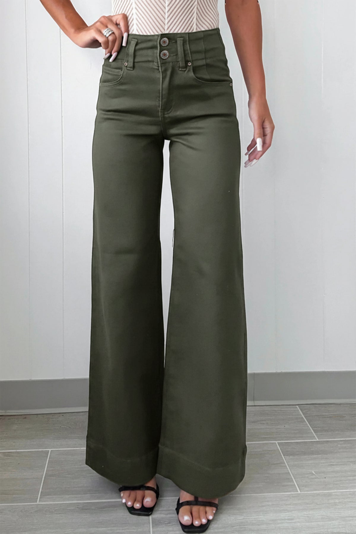 A model wearing olive green  High Waist Wide Leg Jeans with a button fly, paired with black flat sandals.