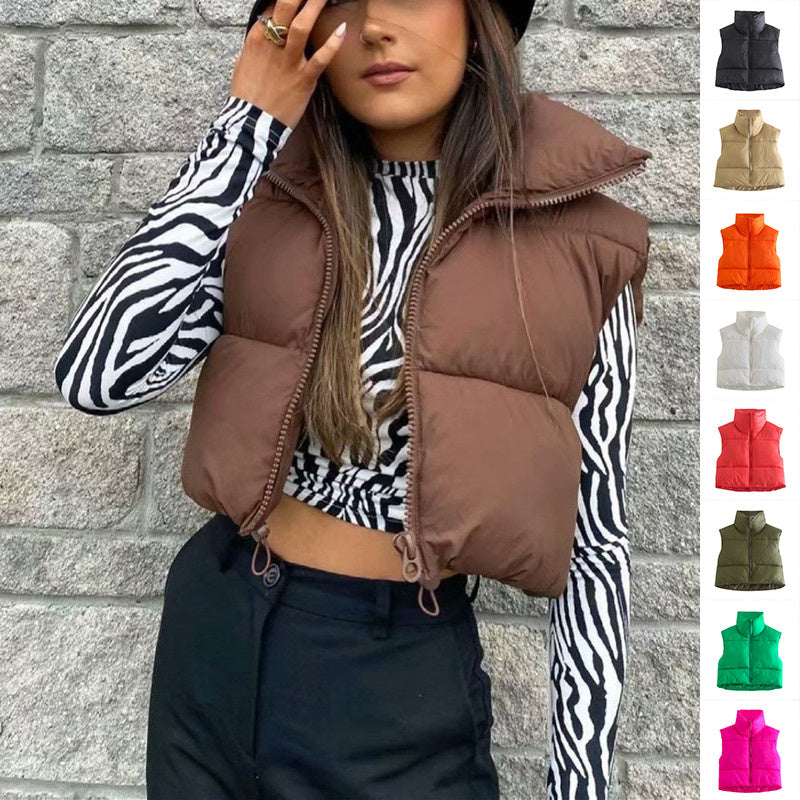 Woman wearing a brown puffer vest over a zebra print shirt with a brick wall background.