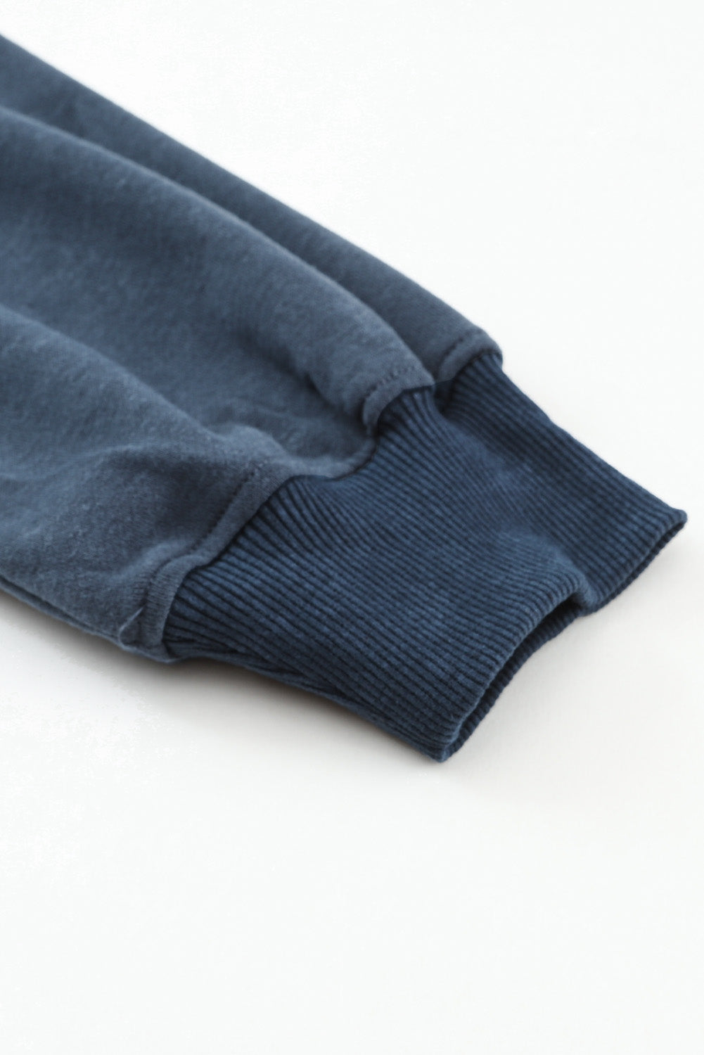 Close-up of a blue sweater sleeve on a white background