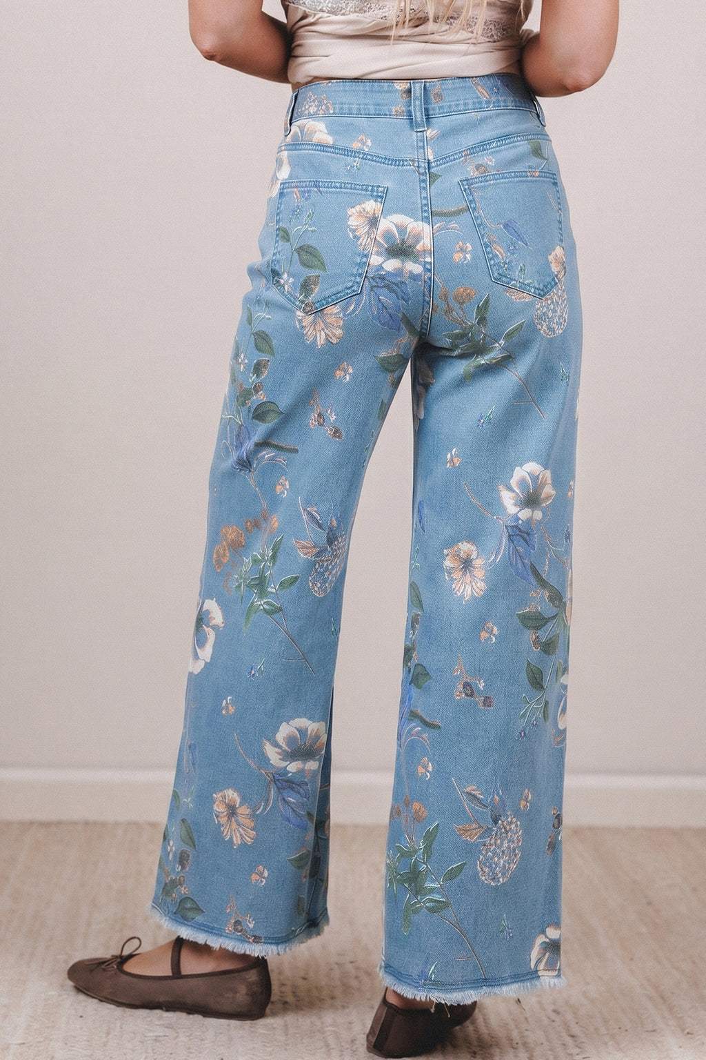 Person wearing blue floral jeans on a plain background