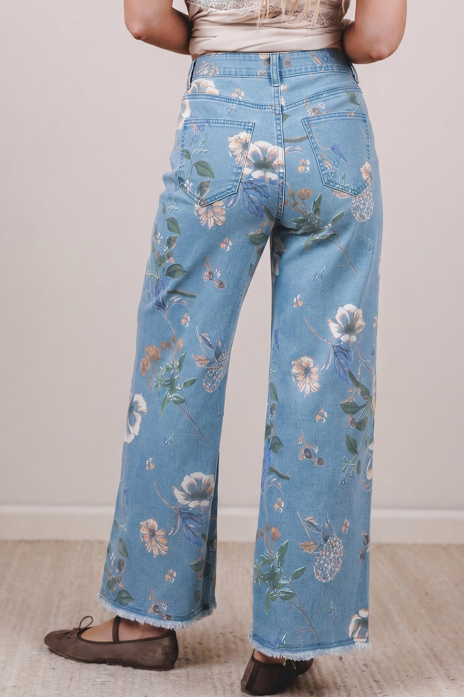 Person wearing blue floral jeans on a plain background