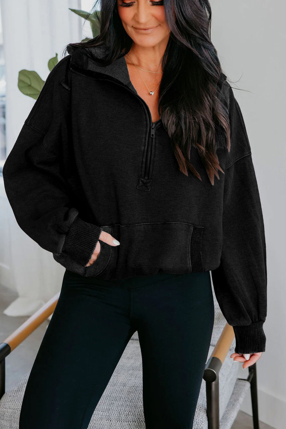 Woman wearing a black jacket and leggings indoors.