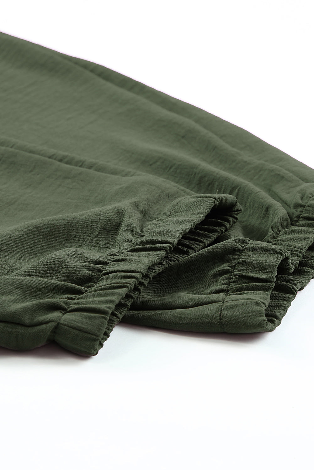 Green fabric with ruffled ankle edges on a white background