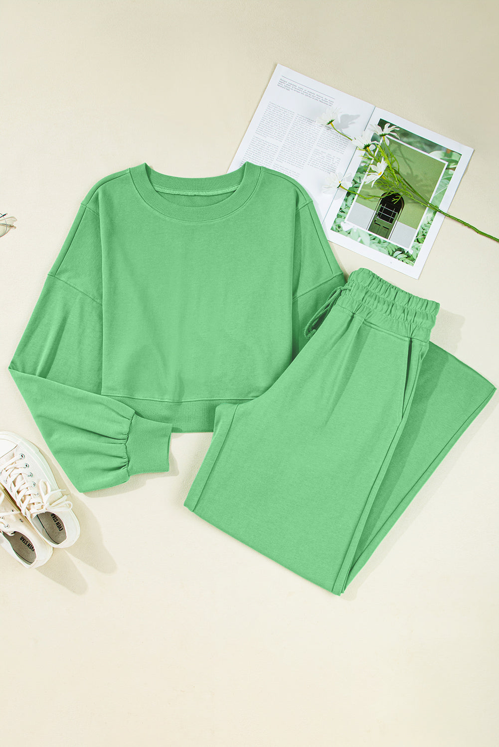 Green pajama set on a light beige surface with a magazine underneath.