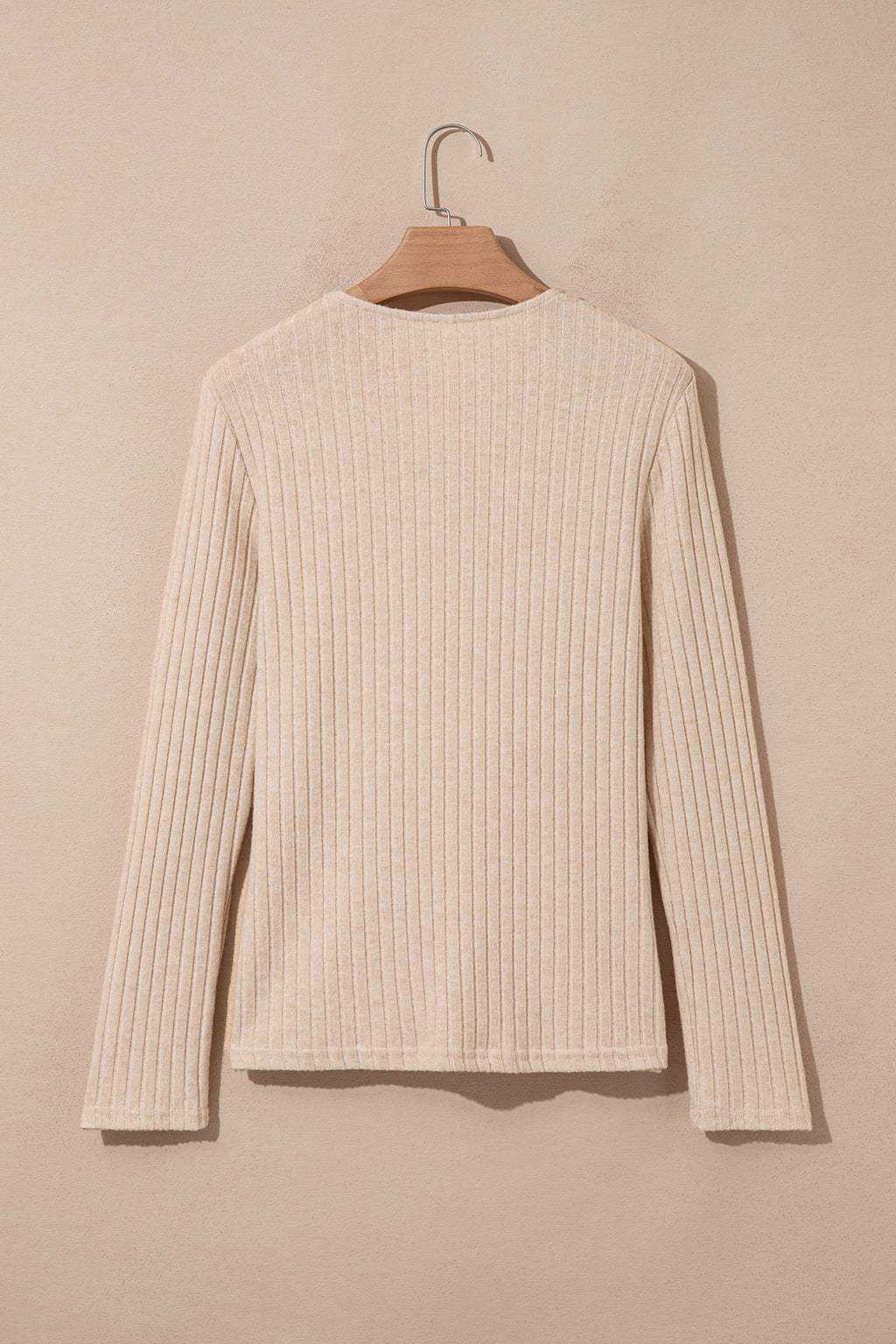 A Ribbed Cowl Neck Women's Blouse in apricot hanging on a wooden hanger back view