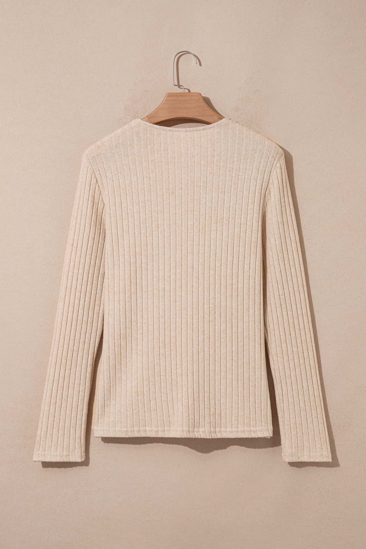 A Ribbed Cowl Neck Women's Blouse in apricot hanging on a wooden hanger back view