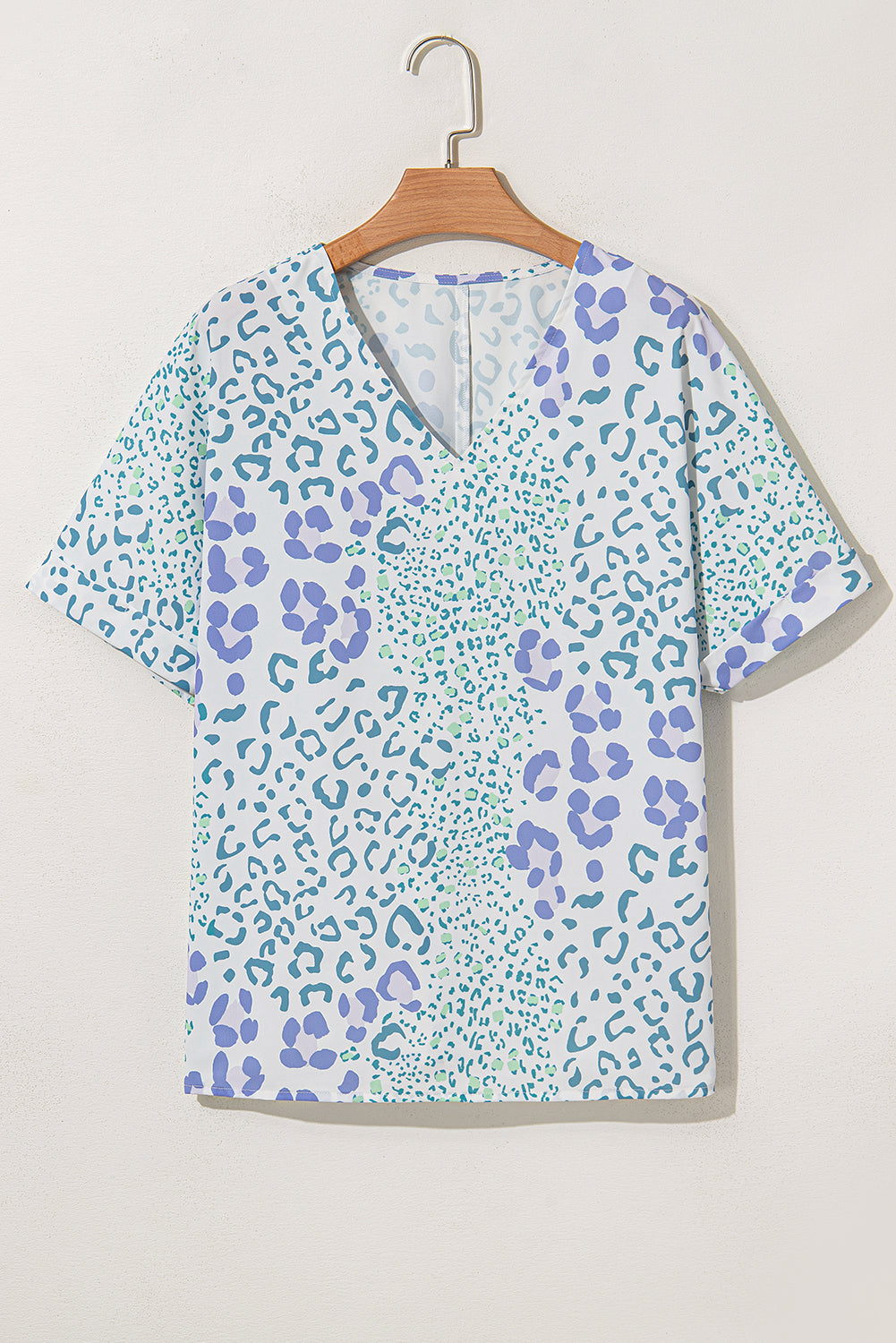 Short-sleeve blouse with blue and green leopard print on a hanger against a white background
