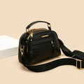 Black handbag with gold accents on a beige background