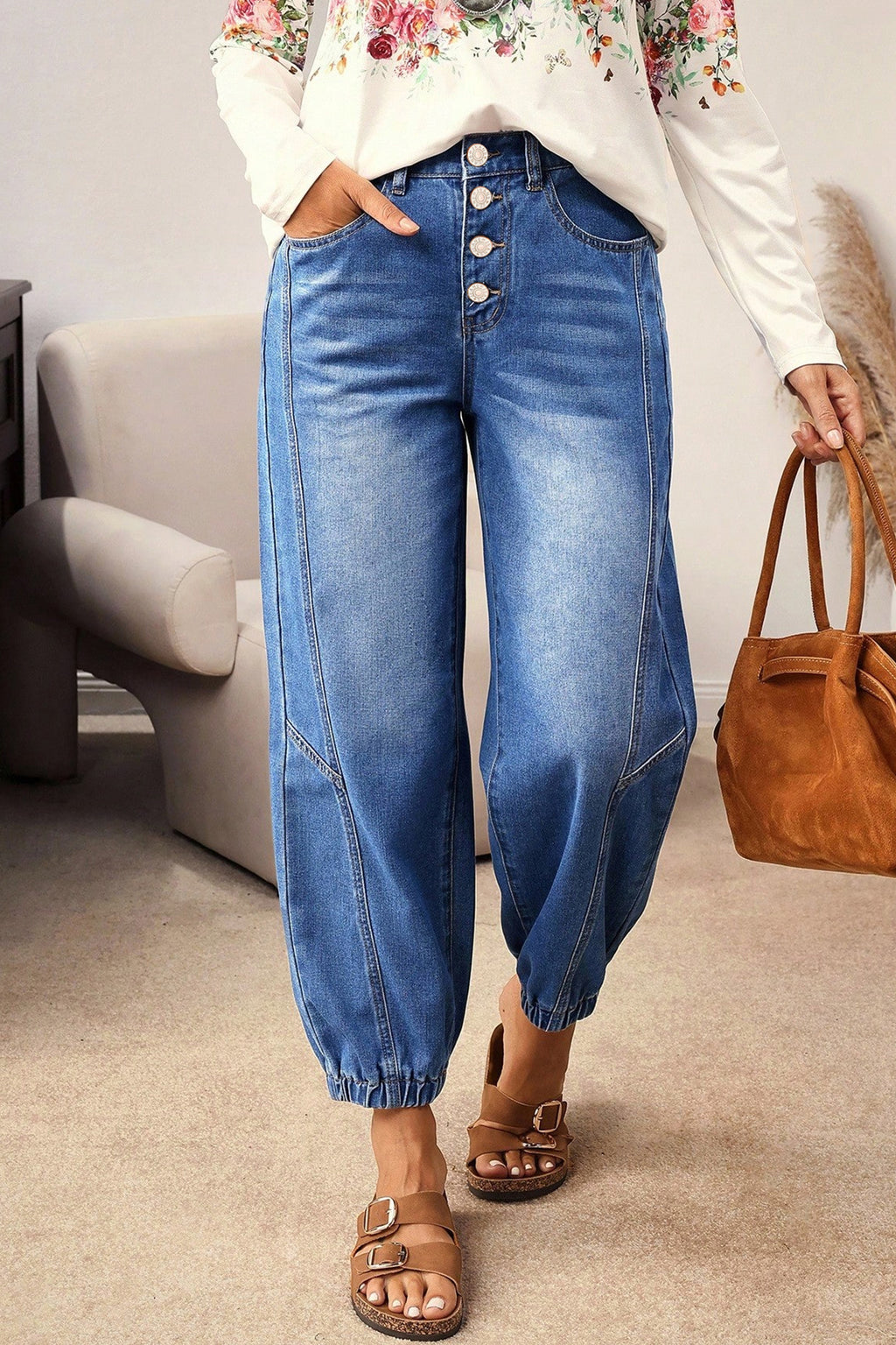 A model wearing Blue Tapered Jeans with a button fly and cuffed harem-style legs