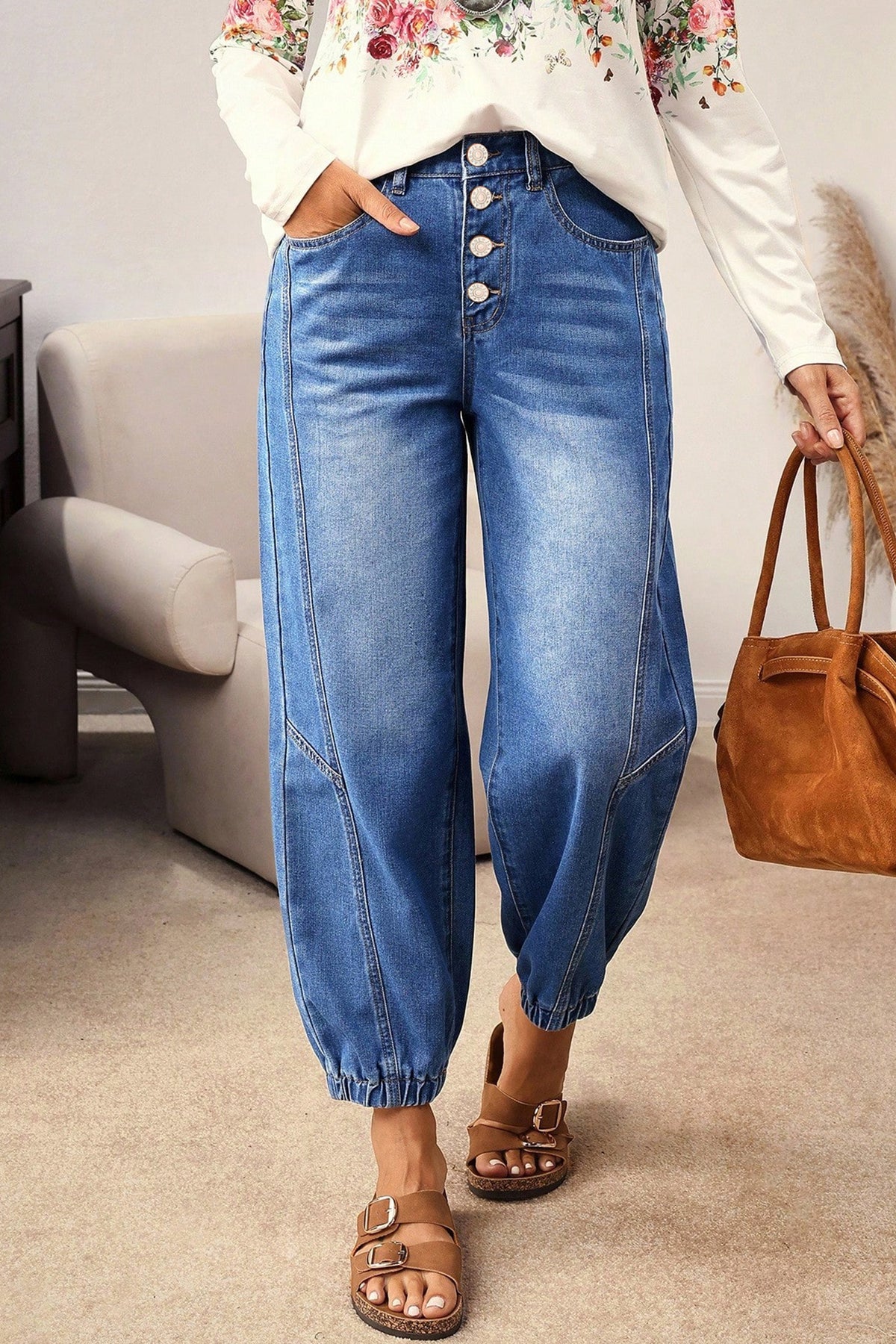 A model wearing Blue Tapered Jeans with a button fly and cuffed harem-style legs