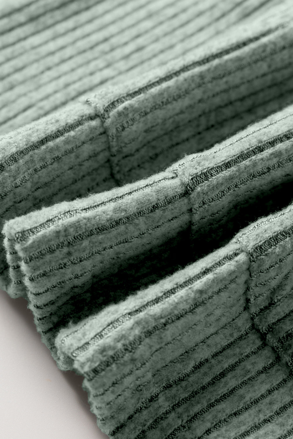 Stack of green textured fabric swatches on a light pink background